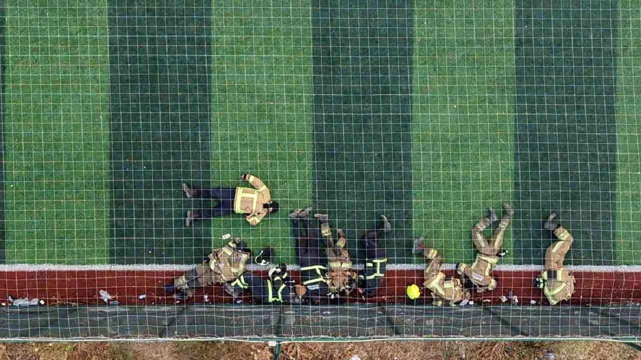 Brandweerlieden die de vlammen bestreden, rustten uit op het kunstgrasveld